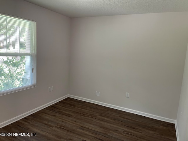 spare room with dark hardwood / wood-style floors, a textured ceiling, and a healthy amount of sunlight