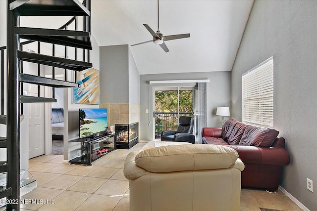 tiled living room with ceiling fan, high vaulted ceiling, and a fireplace