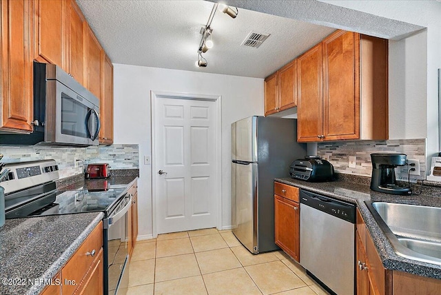 kitchen featuring stainless steel appliances, a textured ceiling, track lighting, and decorative backsplash