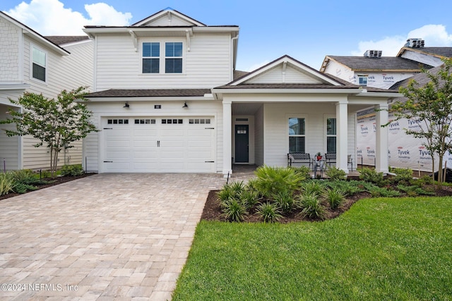 view of front facade with a garage, a porch, and a front lawn