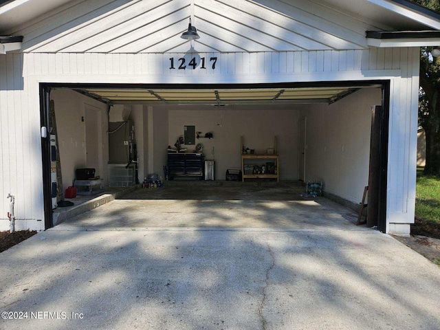 garage with electric panel, driveway, and heating unit