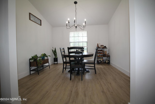 dining space with vaulted ceiling, a notable chandelier, baseboards, and wood finished floors