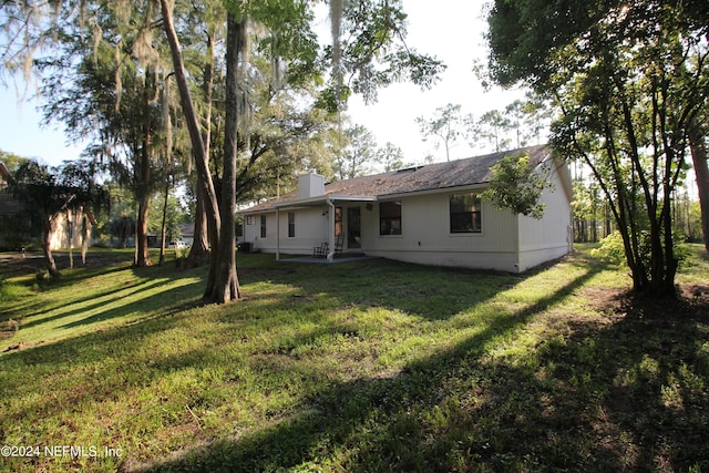 back of house featuring a lawn and a chimney