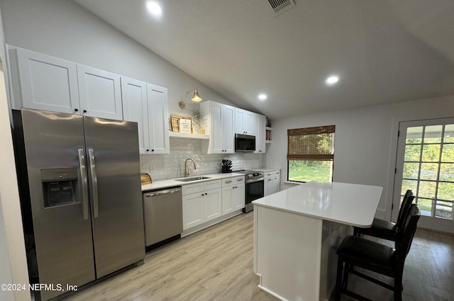 kitchen featuring lofted ceiling, a center island, stainless steel appliances, open shelves, and a sink