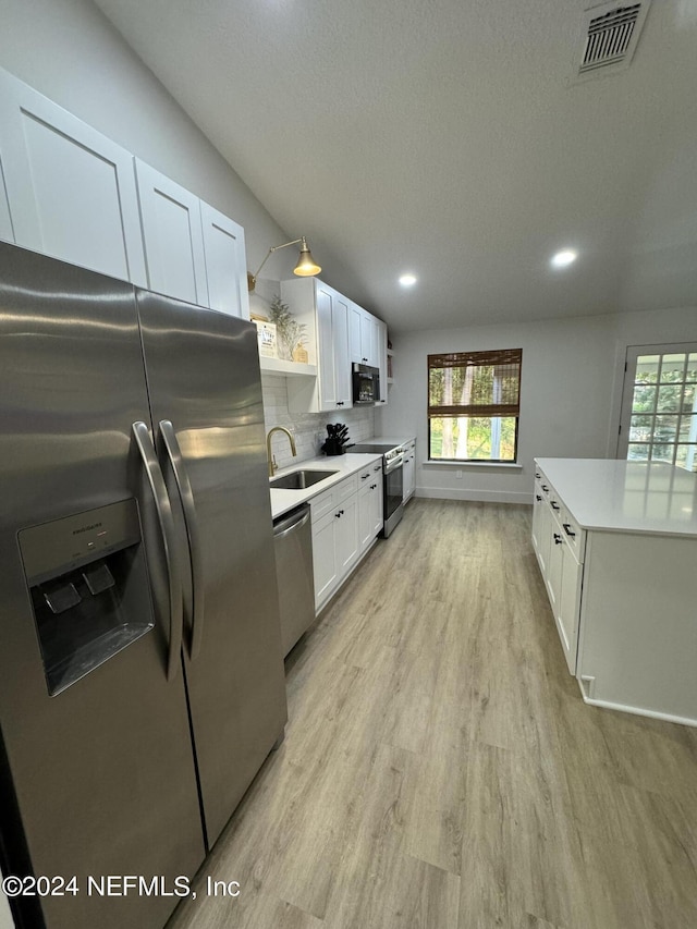 kitchen with stainless steel appliances, a sink, visible vents, white cabinets, and open shelves