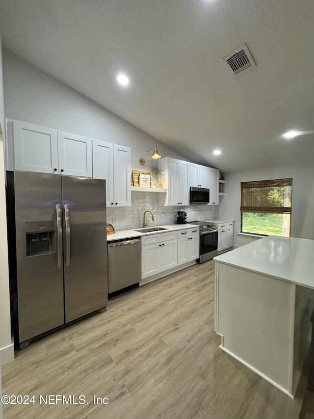 kitchen with lofted ceiling, visible vents, white cabinetry, appliances with stainless steel finishes, and open shelves