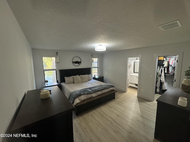 bedroom with a spacious closet, multiple windows, light wood-type flooring, and visible vents