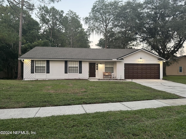 view of front of home with a garage, concrete driveway, and a front lawn