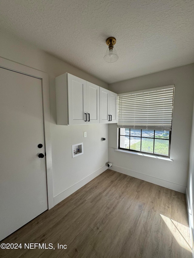 washroom featuring washer hookup, cabinet space, a textured ceiling, and wood finished floors