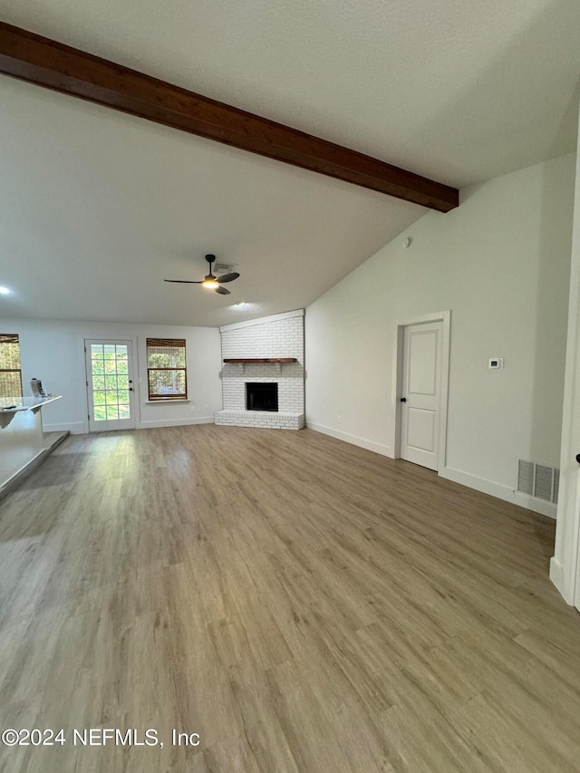 unfurnished living room featuring a fireplace, visible vents, lofted ceiling with beams, a ceiling fan, and baseboards