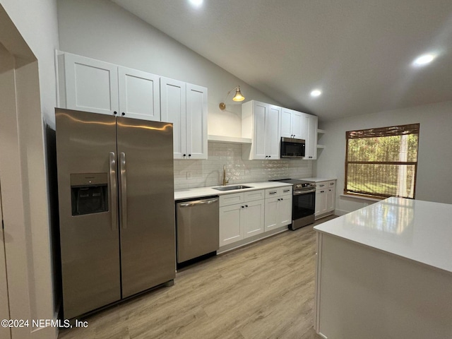 kitchen featuring lofted ceiling, appliances with stainless steel finishes, open shelves, and a sink