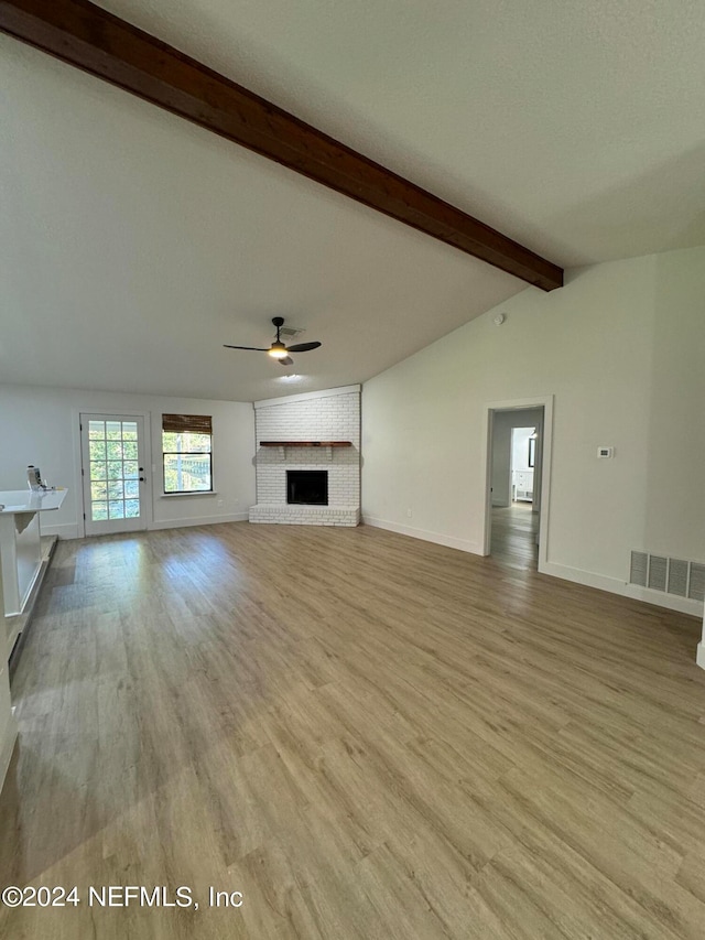 unfurnished living room with vaulted ceiling with beams, ceiling fan, a fireplace, visible vents, and light wood-style floors