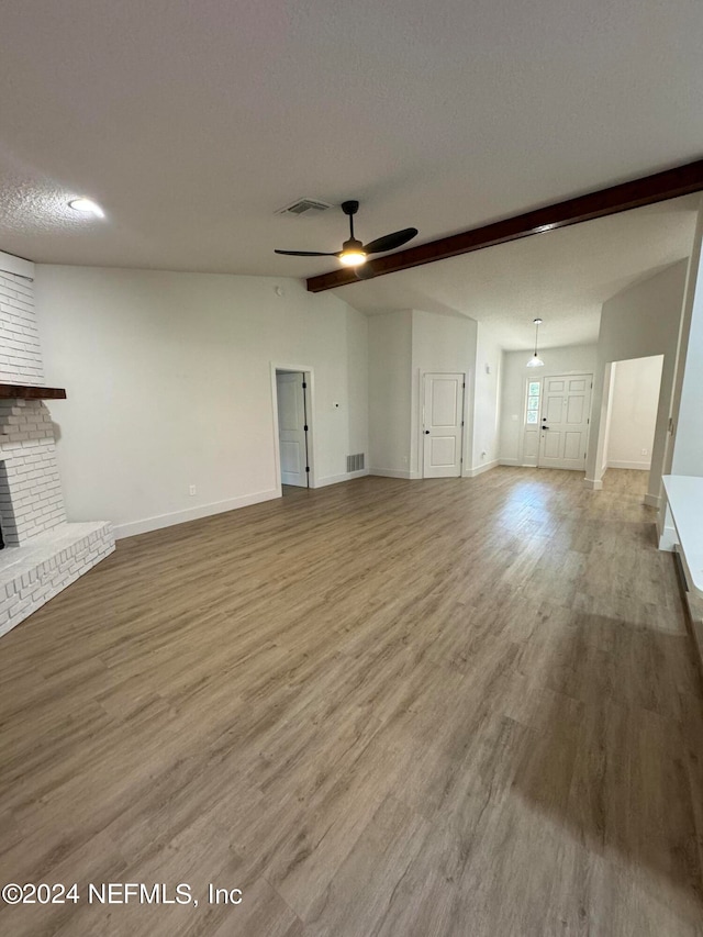 unfurnished living room with a textured ceiling, a fireplace, wood finished floors, and visible vents