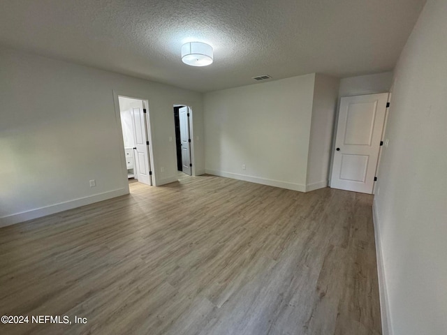 unfurnished room featuring baseboards, a textured ceiling, visible vents, and wood finished floors