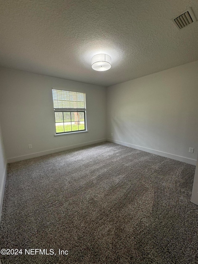 carpeted empty room with baseboards, visible vents, and a textured ceiling