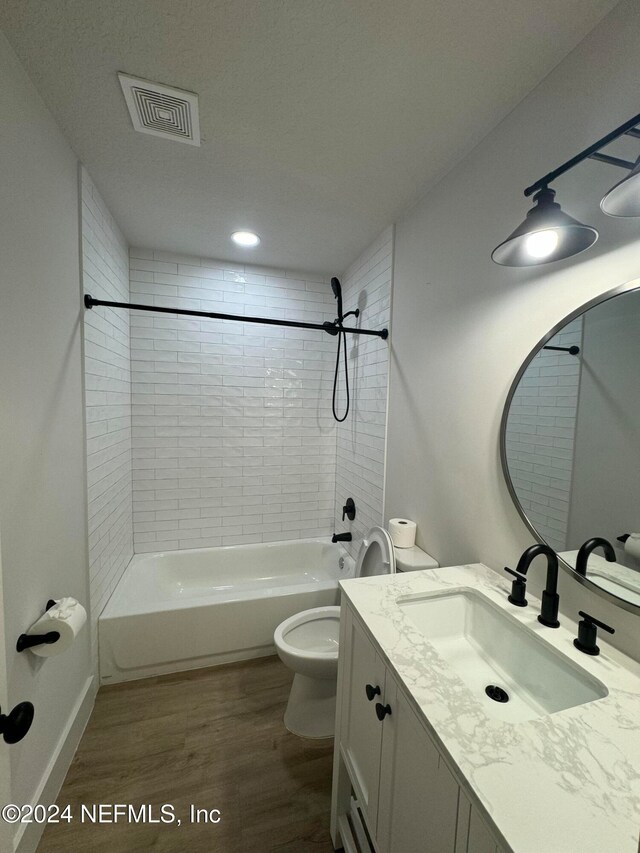 full bath with toilet, wood finished floors, vanity, visible vents, and  shower combination