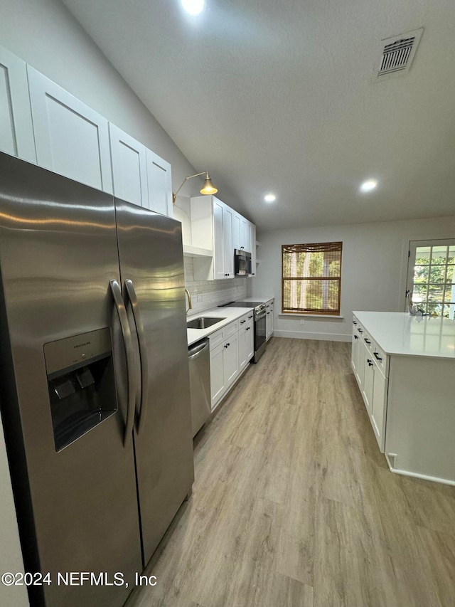 kitchen with light wood finished floors, visible vents, decorative backsplash, appliances with stainless steel finishes, and a sink