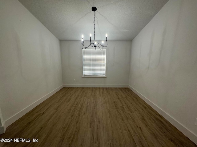 unfurnished dining area featuring a textured ceiling, wood finished floors, and baseboards