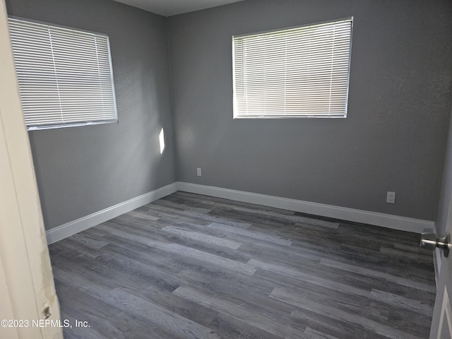 empty room with dark wood-style flooring and baseboards