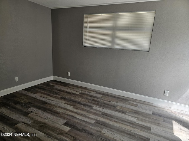 unfurnished room featuring baseboards and dark wood finished floors