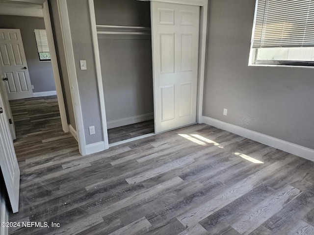 unfurnished bedroom featuring a closet, baseboards, and wood finished floors