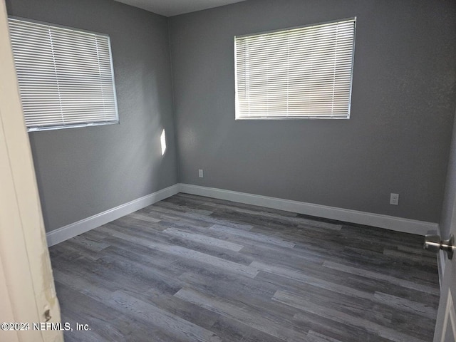 unfurnished room featuring baseboards and dark wood finished floors