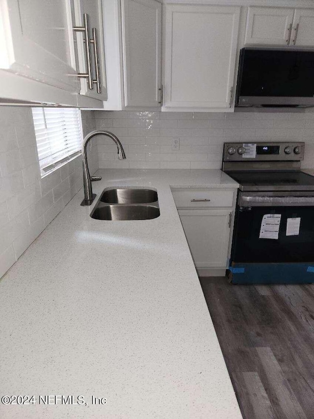 kitchen with tasteful backsplash, light countertops, appliances with stainless steel finishes, white cabinets, and a sink