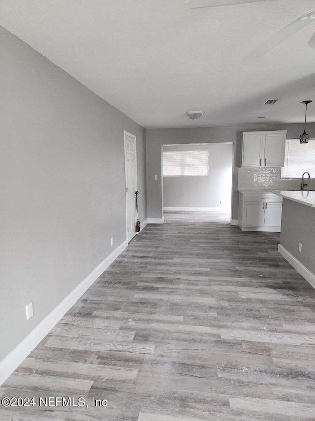 unfurnished living room with light wood-style floors, baseboards, and a sink