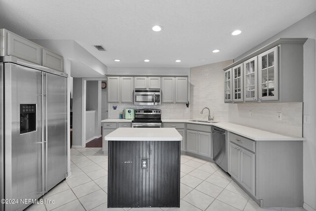 kitchen with tasteful backsplash, stainless steel appliances, gray cabinetry, light tile patterned floors, and sink