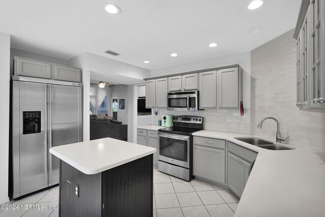 kitchen featuring appliances with stainless steel finishes, sink, light tile patterned flooring, and gray cabinetry