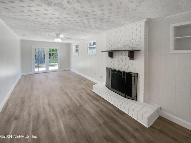 unfurnished living room featuring a textured ceiling, a fireplace, wood finished floors, and baseboards