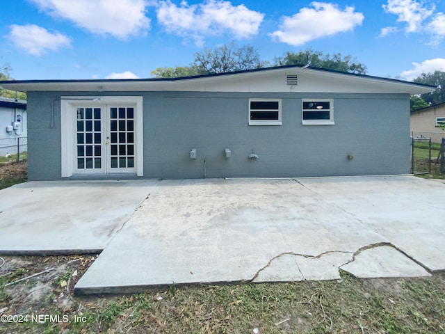 rear view of house featuring concrete block siding, a patio, and french doors