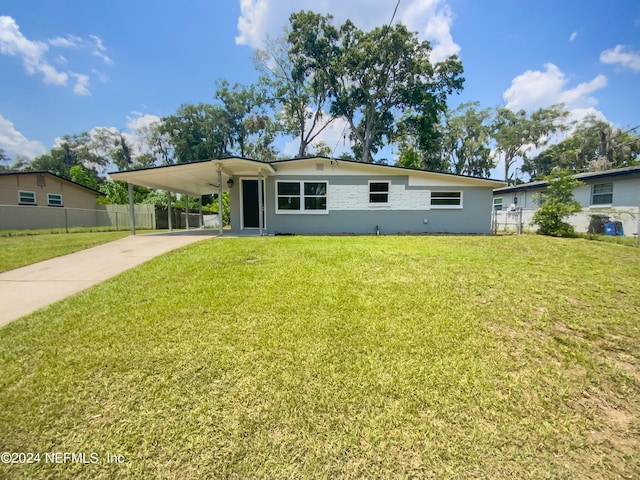 view of front of home with concrete driveway, an attached carport, a front yard, and fence