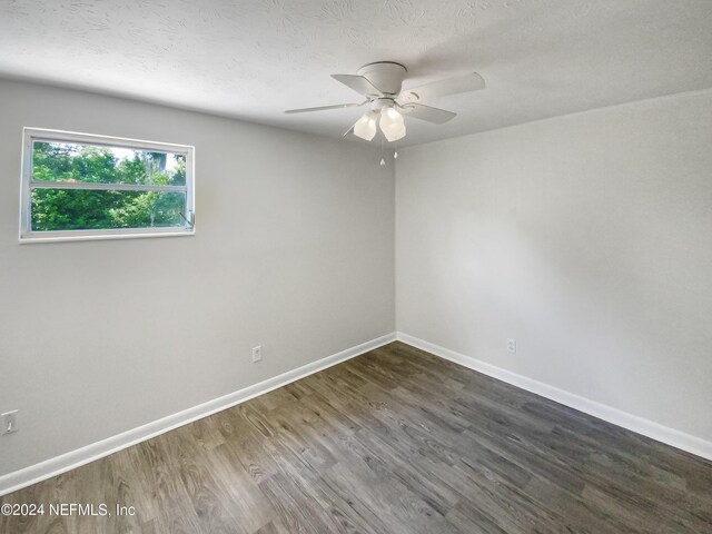 spare room with a ceiling fan, a textured ceiling, baseboards, and dark wood-type flooring