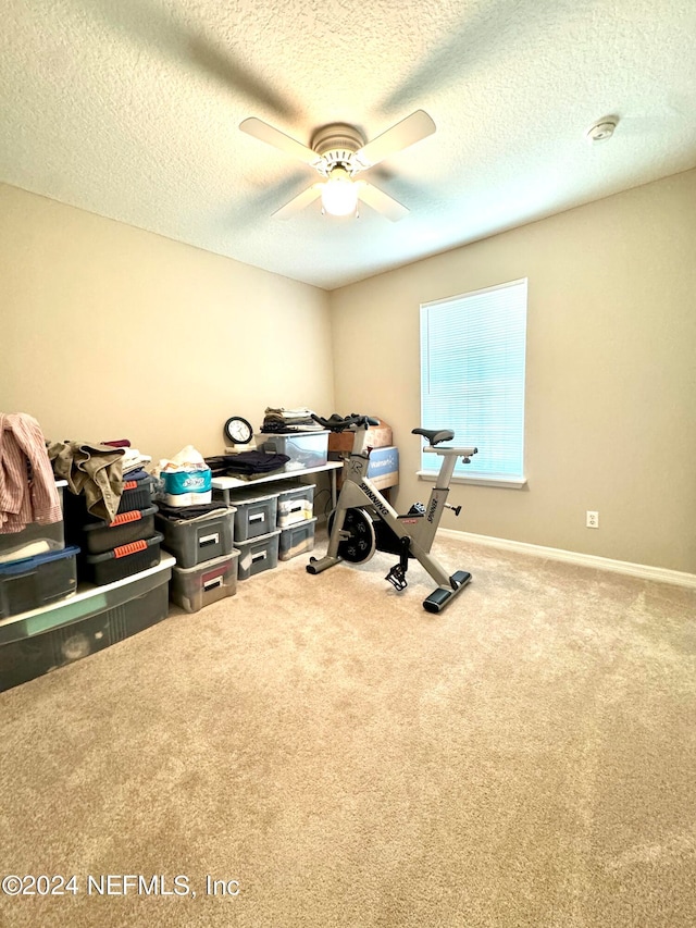 interior space with a textured ceiling, carpet flooring, and ceiling fan