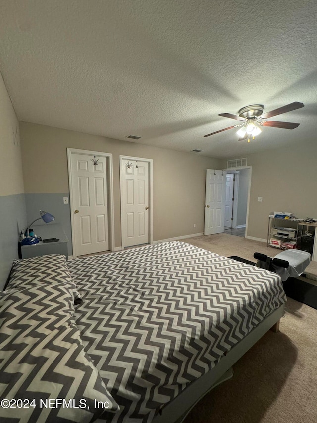 carpeted bedroom with ceiling fan and a textured ceiling