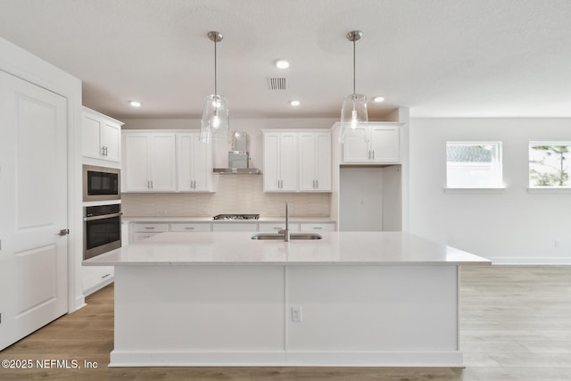 kitchen featuring white cabinetry, appliances with stainless steel finishes, and an island with sink