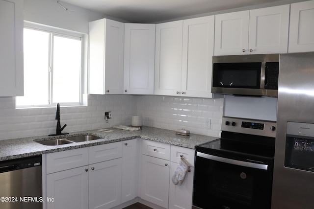 3037 Ribault Scenic Dr, Jacksonville, FL 32208 - kitchen featuring tasteful backsplash, white cabinets, a sink, and stainless steel appliances