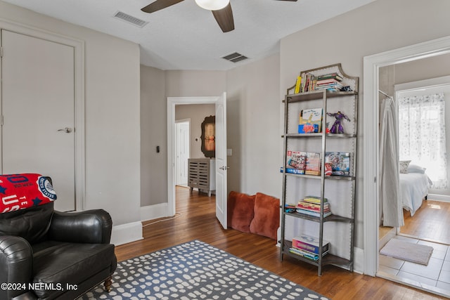 sitting room featuring dark wood-type flooring and ceiling fan