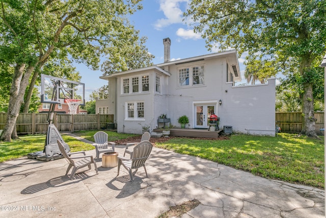 back of house with a wooden deck, a patio, and a yard