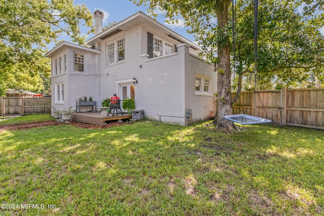 back of property with central AC, a deck, and a yard