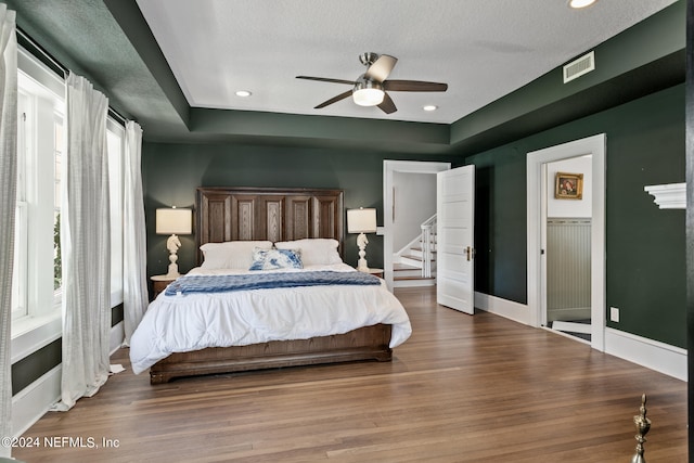 bedroom with ceiling fan, a textured ceiling, and wood-type flooring