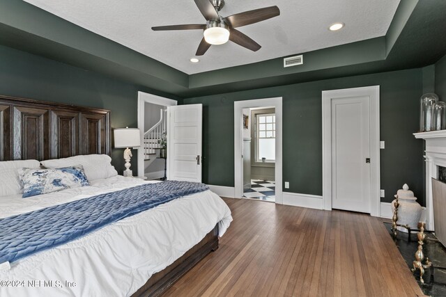 bedroom with hardwood / wood-style floors, ceiling fan, and ensuite bathroom