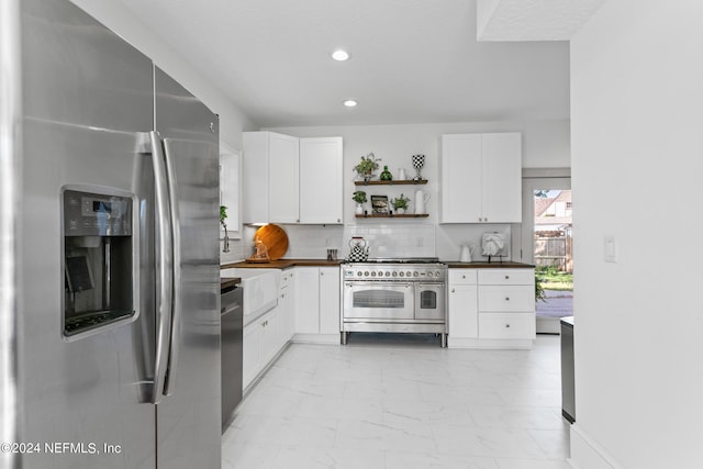 kitchen with appliances with stainless steel finishes, white cabinetry, light tile patterned floors, and tasteful backsplash