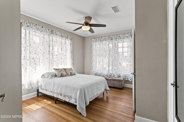 bedroom with light wood-type flooring, ceiling fan, and multiple windows