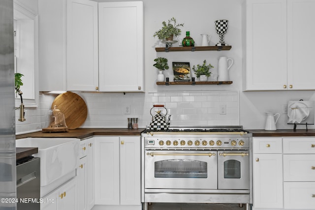 kitchen with double oven range, white cabinets, and backsplash