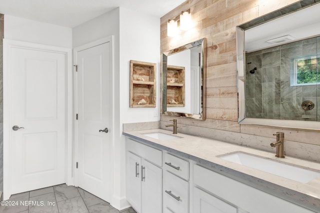 full bath featuring double vanity, tiled shower, marble finish floor, and a sink