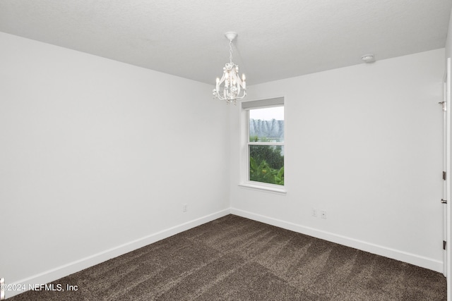 unfurnished room featuring a notable chandelier, baseboards, and dark colored carpet