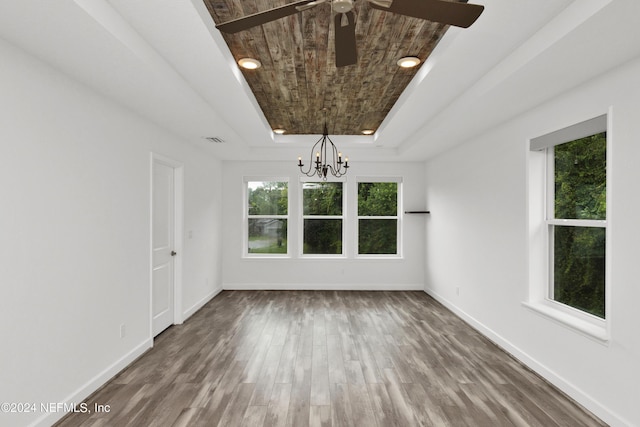 empty room with baseboards, a raised ceiling, visible vents, and wood finished floors