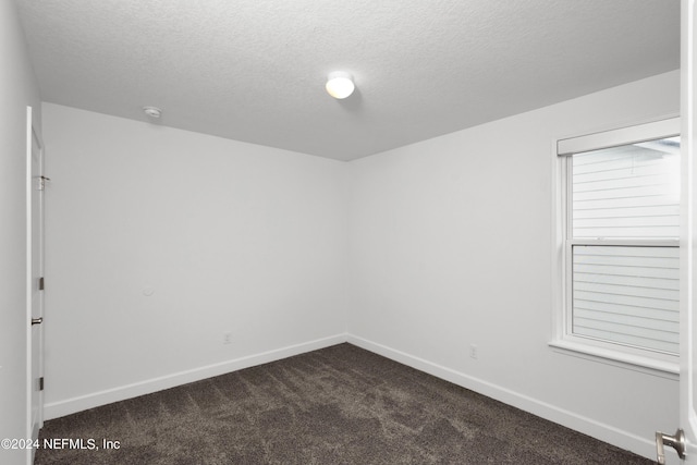 unfurnished room featuring dark carpet, a textured ceiling, and baseboards